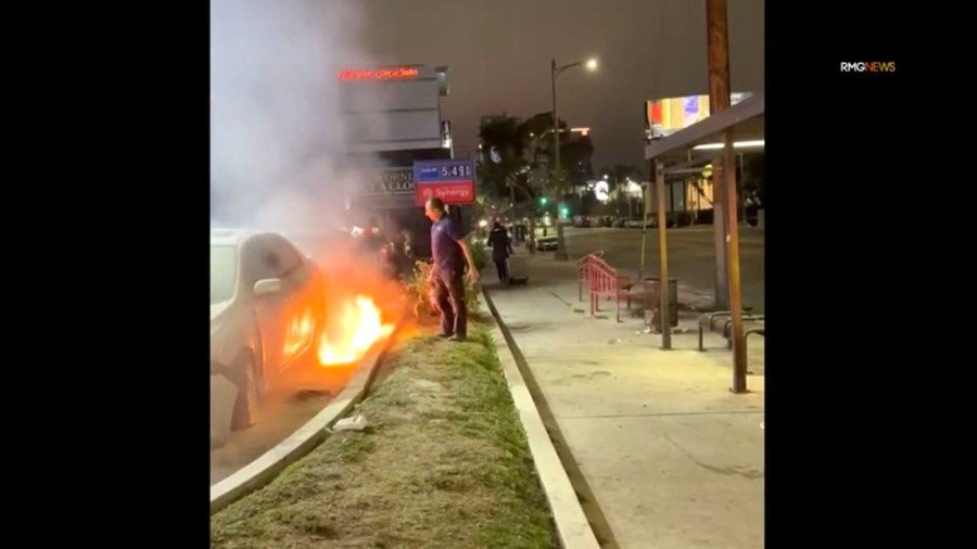 Un transeúnte con un extintor interviene cuando el sospechoso prendió fuego a un automóvil en una gasolinera de Hollywood el 27 de diciembre de 2024. (RMG)